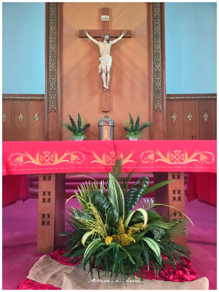 an altar with flowers, plants and a crucifix in front of it