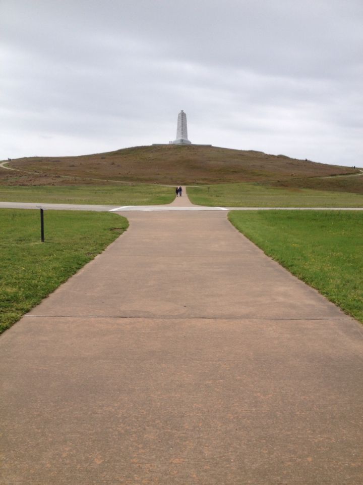 an empty path leading to a monument on top of a hill