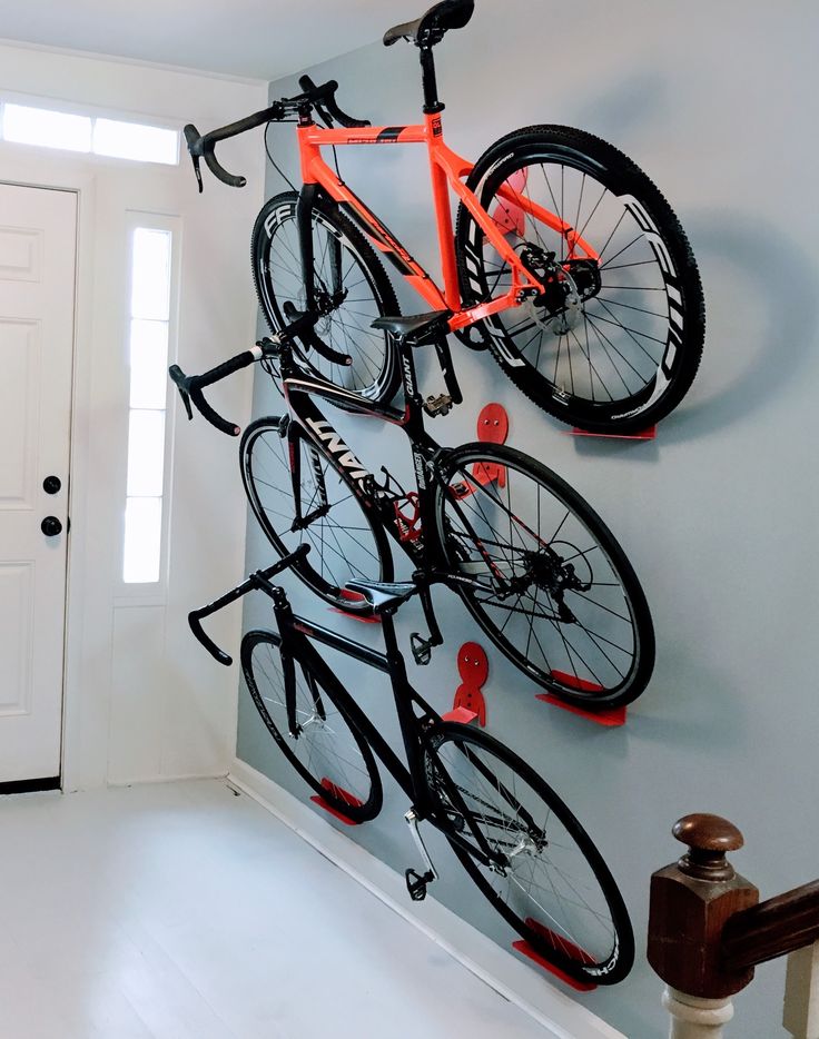 a bicycle mounted to the side of a wall with two bikes hanging from it's hooks