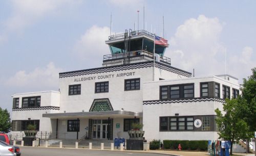 an airport building with cars parked on the side of the road in front of it