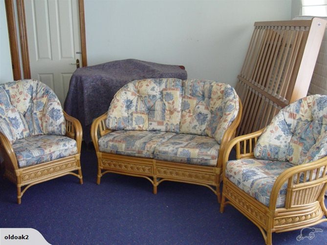 three wicker chairs and two couches in a living room with blue carpeting