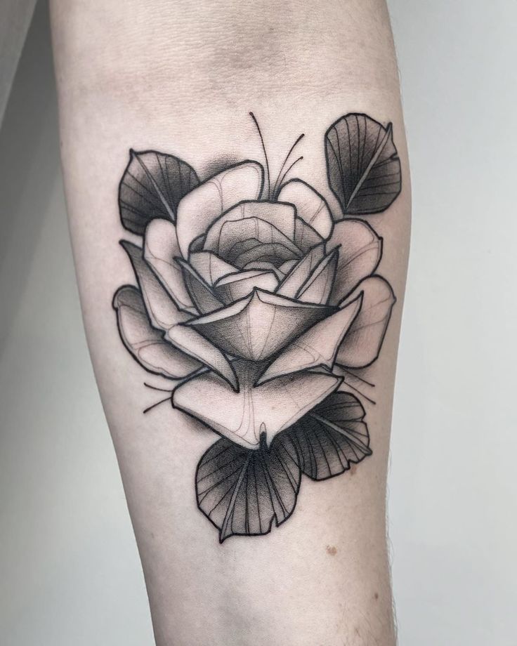 a black and white rose tattoo on the right leg with leaves around it's petals