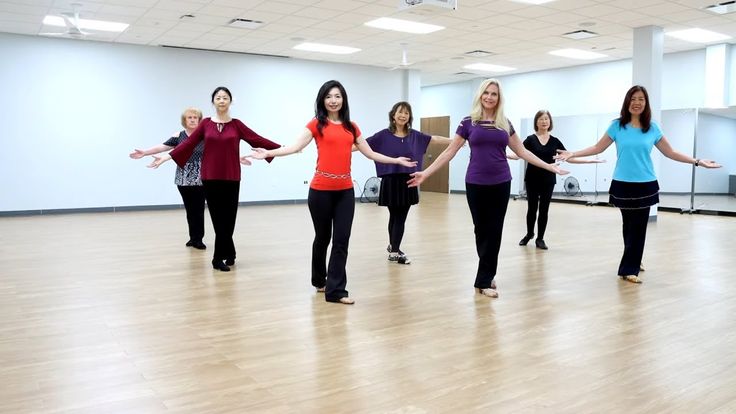 a group of women standing on top of a wooden floor next to each other in a room