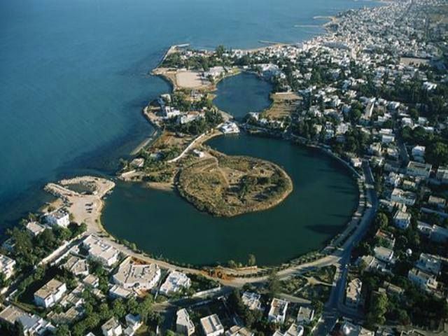 an aerial view of a small island in the middle of some water with houses around it