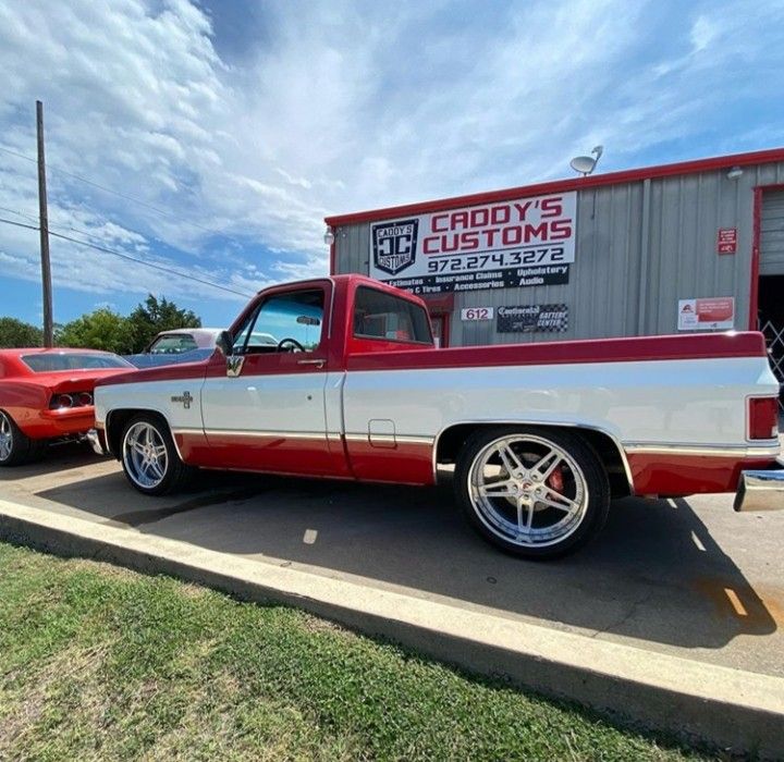 a red and white truck parked in front of a building next to another red car