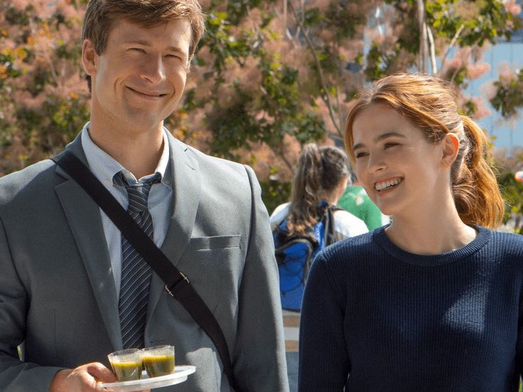 a man in a suit and tie standing next to a woman holding a plate with food on it