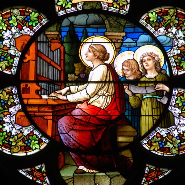 a stained glass window with an image of two women sitting at a table and playing the organ