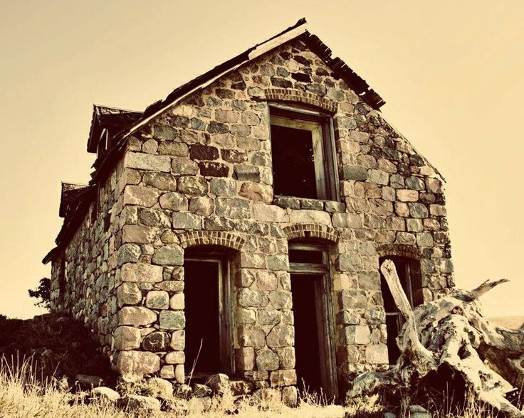 an old stone house sitting on top of a hill