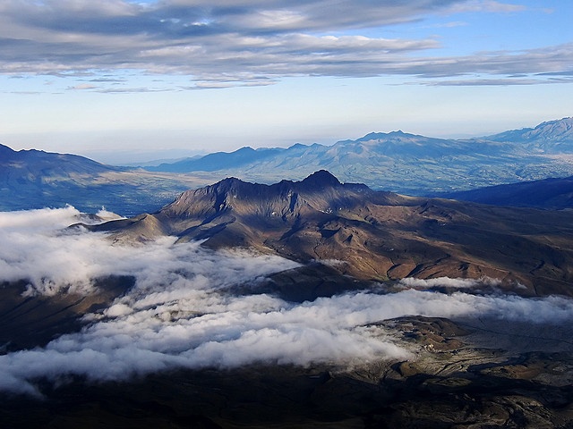 an aerial view of mountains and clouds in the sky