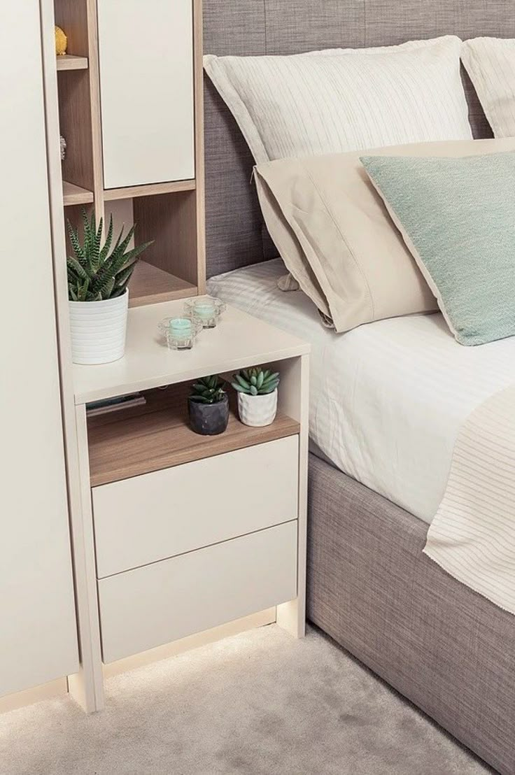 a bed sitting next to a nightstand with a potted plant on it