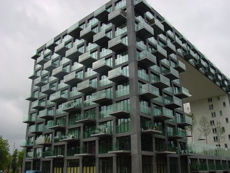 a very tall building with balconies on the top and bottom floors in front