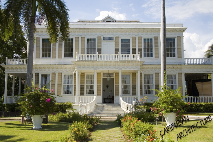 a large white house sitting on top of a lush green field next to palm trees