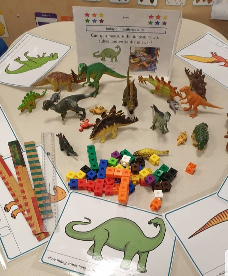 a table topped with lots of toy dinosaurs and legos on top of paper plates