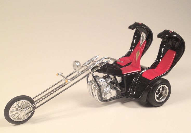 a toy motorcycle with two seats on the front and rear wheels, in black and red