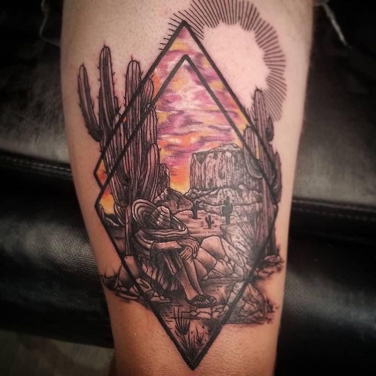 a man's arm with a tattoo on it that has a desert scene in the background