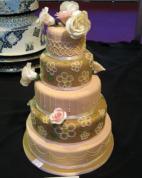 a three tiered cake with flowers on it sitting on top of a black table