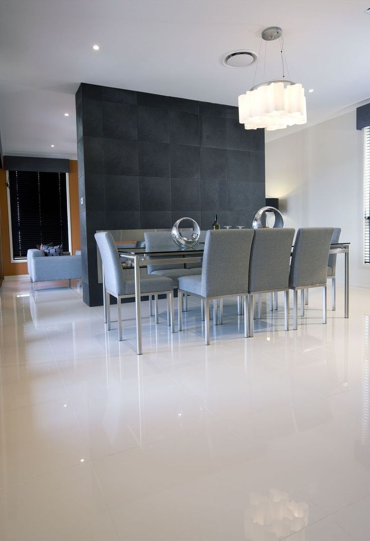 a dining room table and chairs in front of a black wall with white tiles on the floor