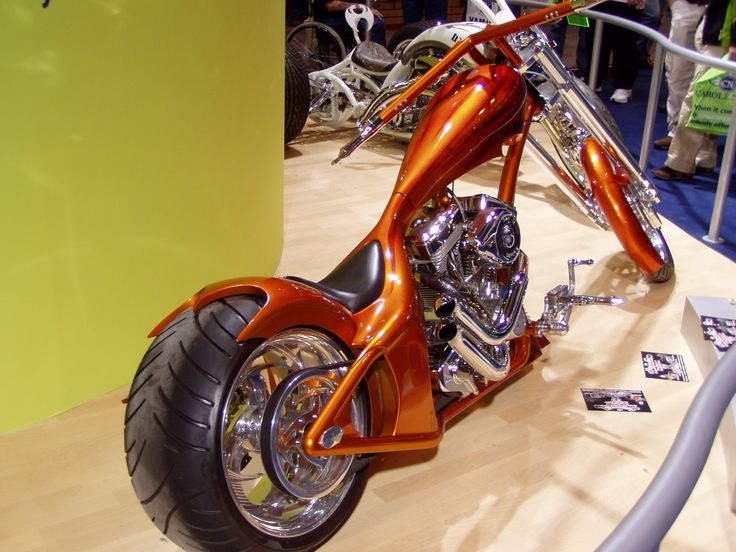 an orange motorcycle parked on top of a wooden floor