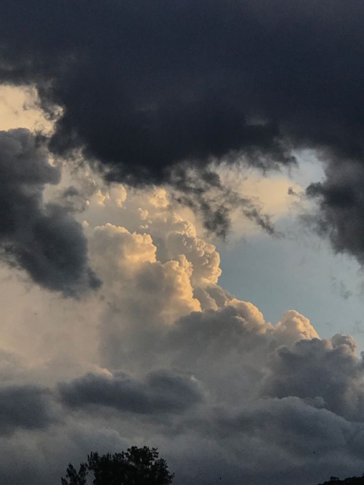 the sky is full of clouds and some trees in front of an overcast sky