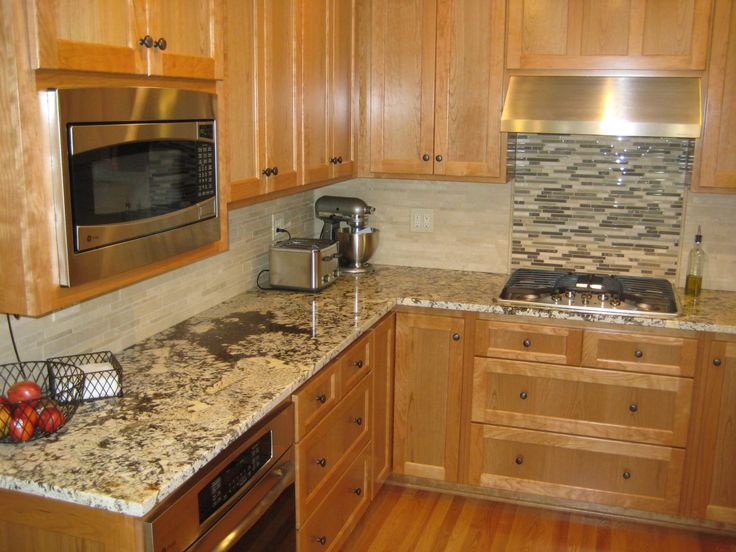 a kitchen with wooden cabinets and granite counter tops, stainless steel appliances and an oven