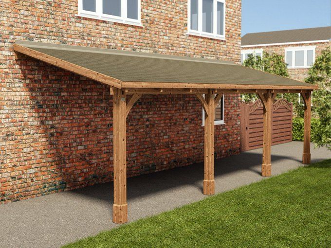 a wooden carport in front of a brick building with grass and bushes around it