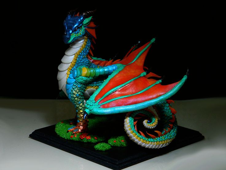 a colorful dragon figurine sitting on top of a white table next to a black background