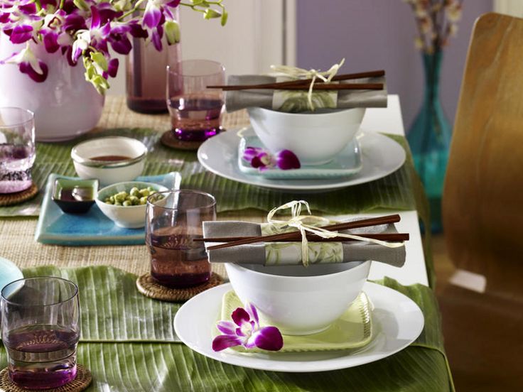 the table is set with purple flowers and bowls