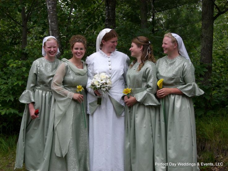 a group of women standing next to each other wearing dresses and holding flowers in their hands