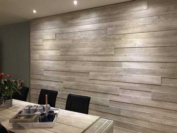 a dining room table with black chairs and a wooden wall behind it