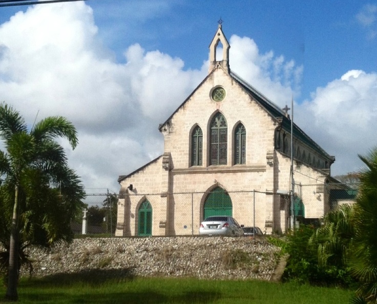 an old church with a car parked in front and palm trees around it on a sunny day