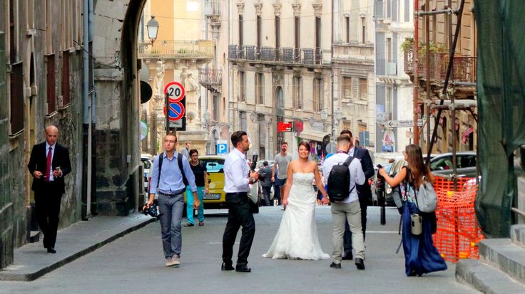 a bride and groom are walking down the street in front of some buildings with people