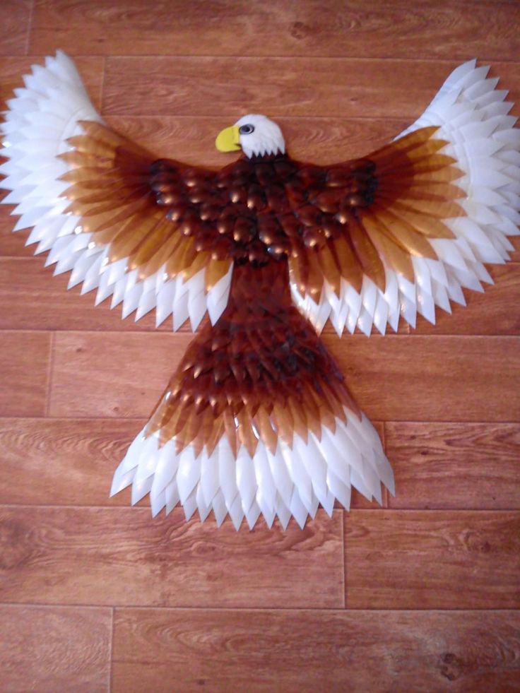 an eagle made out of paper sitting on top of a wooden floor