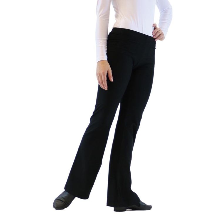 a woman in white shirt and black pants standing with her hands behind her back to the camera