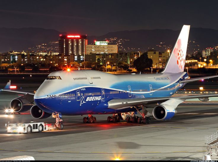 an airplane is parked on the tarmac at night with city lights in the background