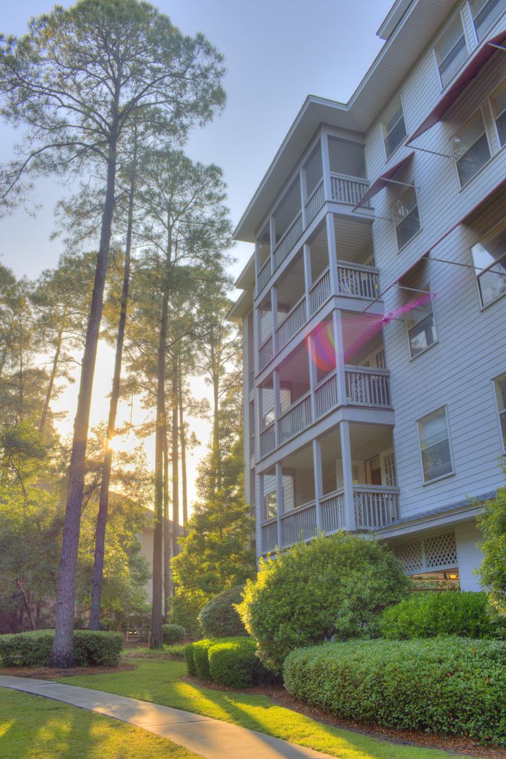 an apartment building with balconies and trees in the foreground, at sunset