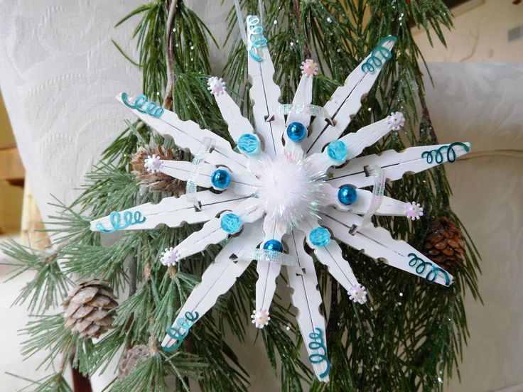 a snowflake ornament hanging from a christmas tree with blue and white ornaments