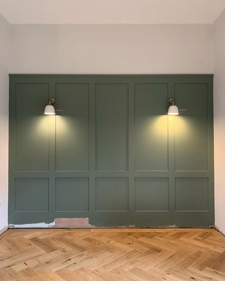 an empty room with three lights on the wall and wood flooring in front of it