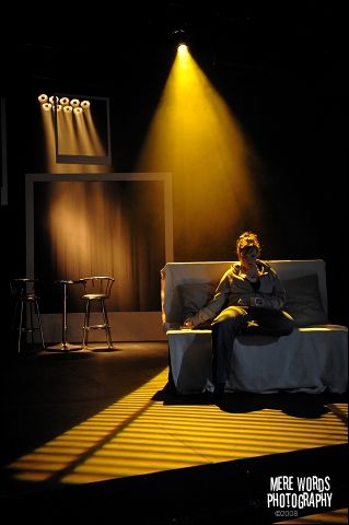 a man sitting on top of a couch under a spotlight