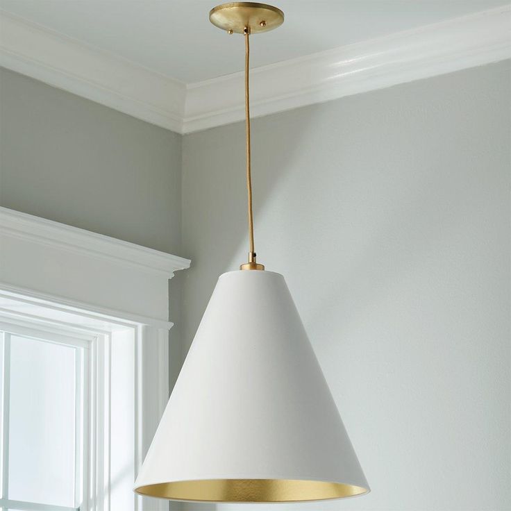 a white lamp hanging from the ceiling in a room with gray walls and gold trim