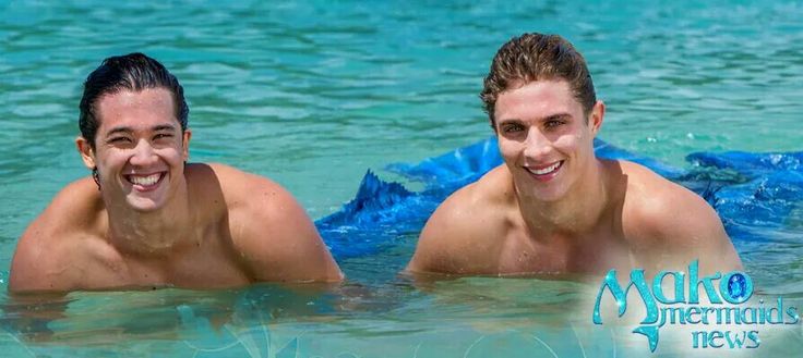 two young men are swimming in the water with blue tarps on their backs and one is smiling at the camera