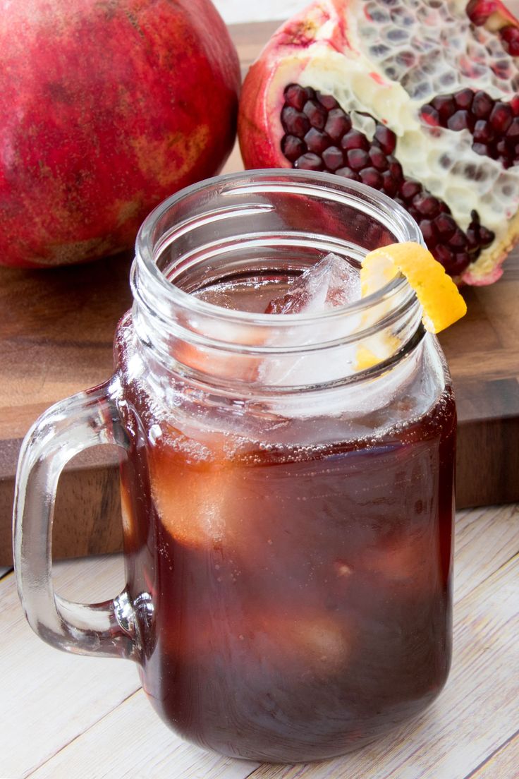 a glass jar filled with liquid next to pomegranate