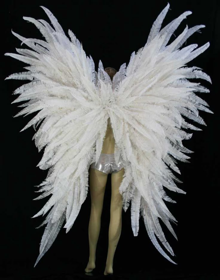 a mannequin with white feathers on it's head and legs, standing in front of a black background