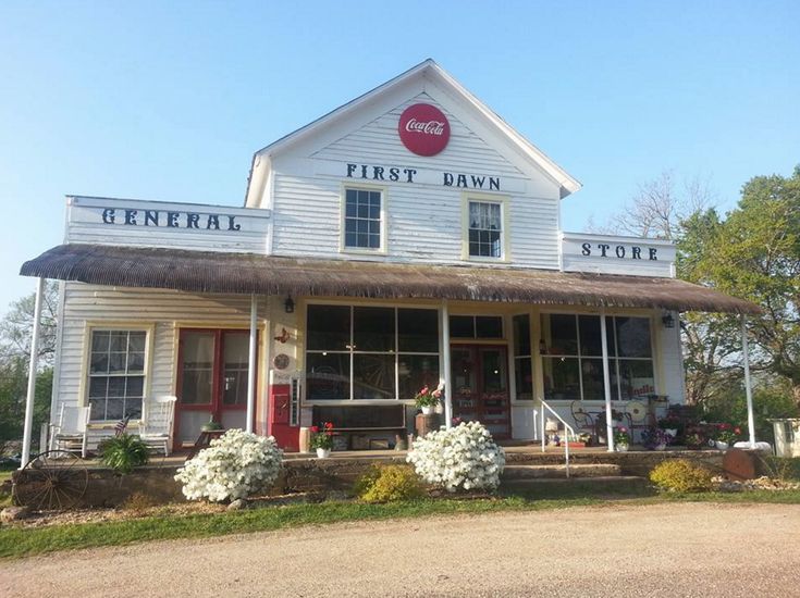 a white building with flowers in front of it and the words, first dawn store