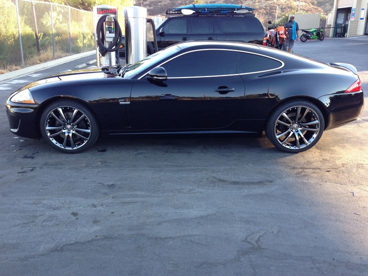 a black sports car parked in front of a gas station with an electric charger