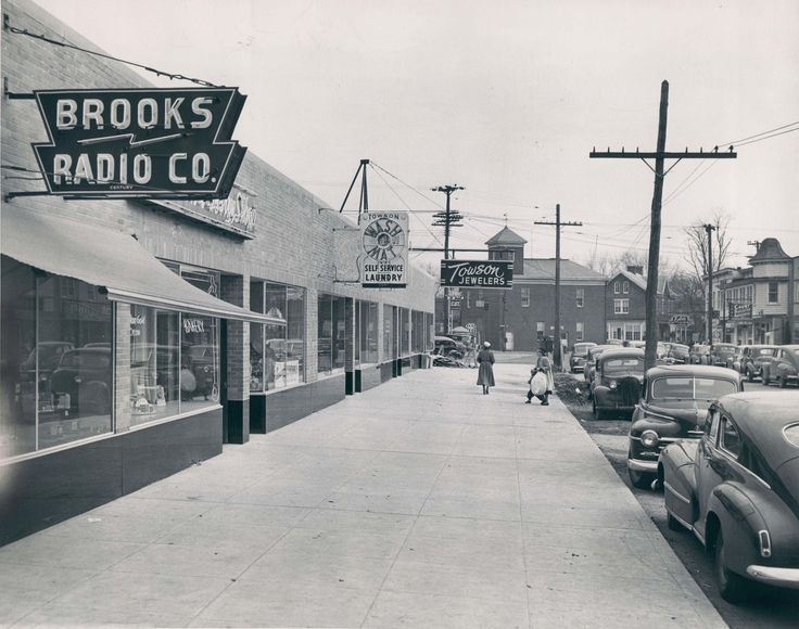 an old black and white photo of people walking on the sidewalk in front of a radio company