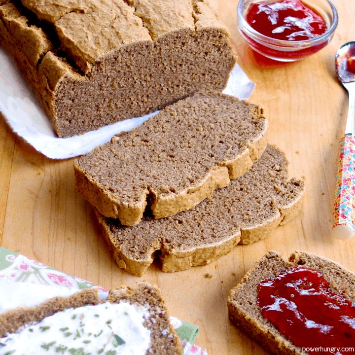 sliced loaf of bread sitting on top of a wooden table next to butter and jelly