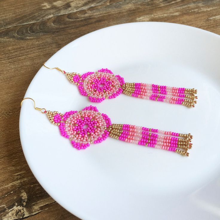 Add brightness and floral vibe to your everyday look with the help of these hot pink beaded earrings. These huichol flower earrings inspired by Mexican style. These statement mandala earrings are made from high-quality Czech seed beads and stainless steel accessories. No doubts, these fuschia seed bead earrings become a bright detail of any look and a unique gift for anybody who loves artisan jewelry in tribal style. 100% top quality handmade earrings. Length: 4.72'' / 12 cm Flower diameter: 1.42'' / 3,6 cm Fringe length: 2.17'' / 5,5 cm Materials:  - Czech seed beads - stainless steel accessories. The real color of the item may be slightly different from the picture shown on website caused by the brightness of your monitor. If you have special size requirements, please send me a letter ab Beaded Fuschia Flower Earrings, Traditional Pink Beaded Earrings With Dangling Beads, Pink Beaded Earrings With Dangling Beads For Festivals, Pink Beaded Earrings With Fringe, Pink Beaded Drop Flower Earrings, Pink Dangle Flower Earrings With Colorful Beads, Pink Beaded Drop Earrings For Festivals, Pink Dangle Beaded Earrings For Festival, Pink Handmade Tassel Earrings For Festivals