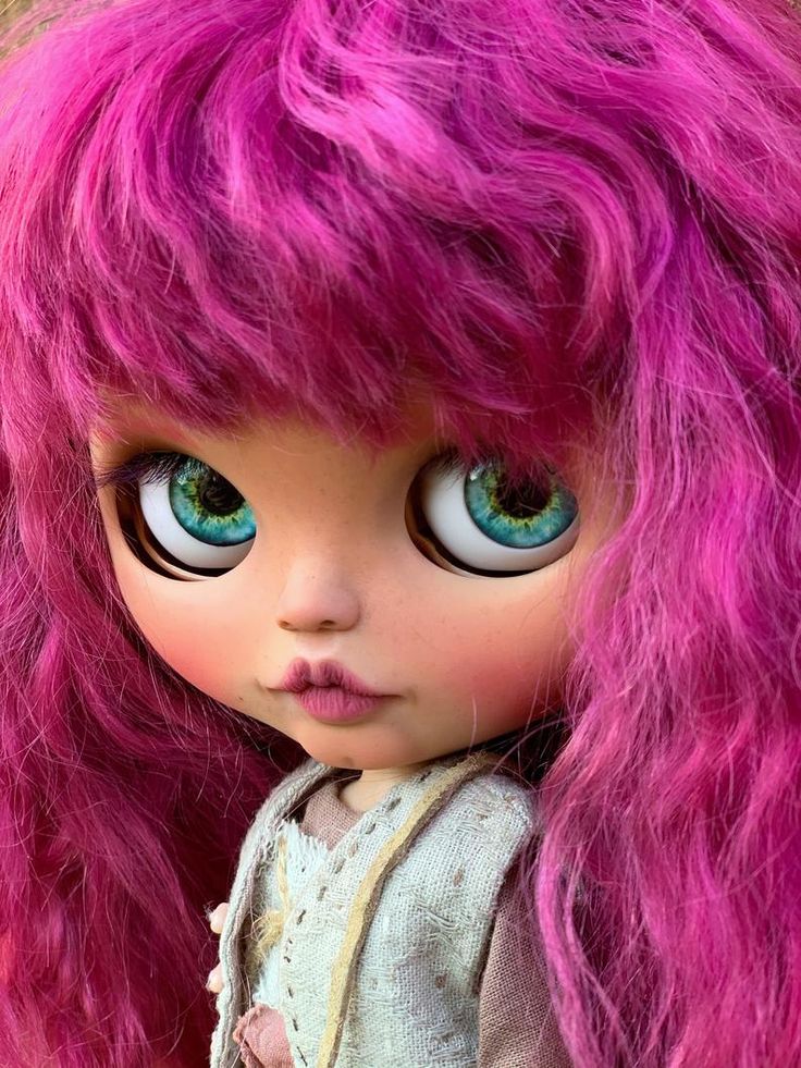 a close up of a doll with pink hair and blue eyes, wearing a dress