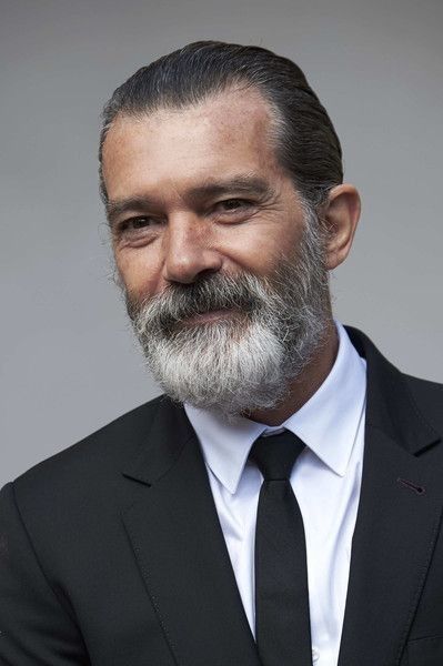 a man in a suit and tie with a beard smiling at the camera while wearing a white shirt and black tie