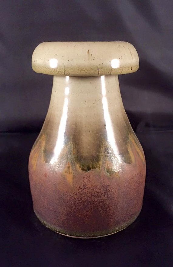 a brown and tan vase sitting on top of a black table